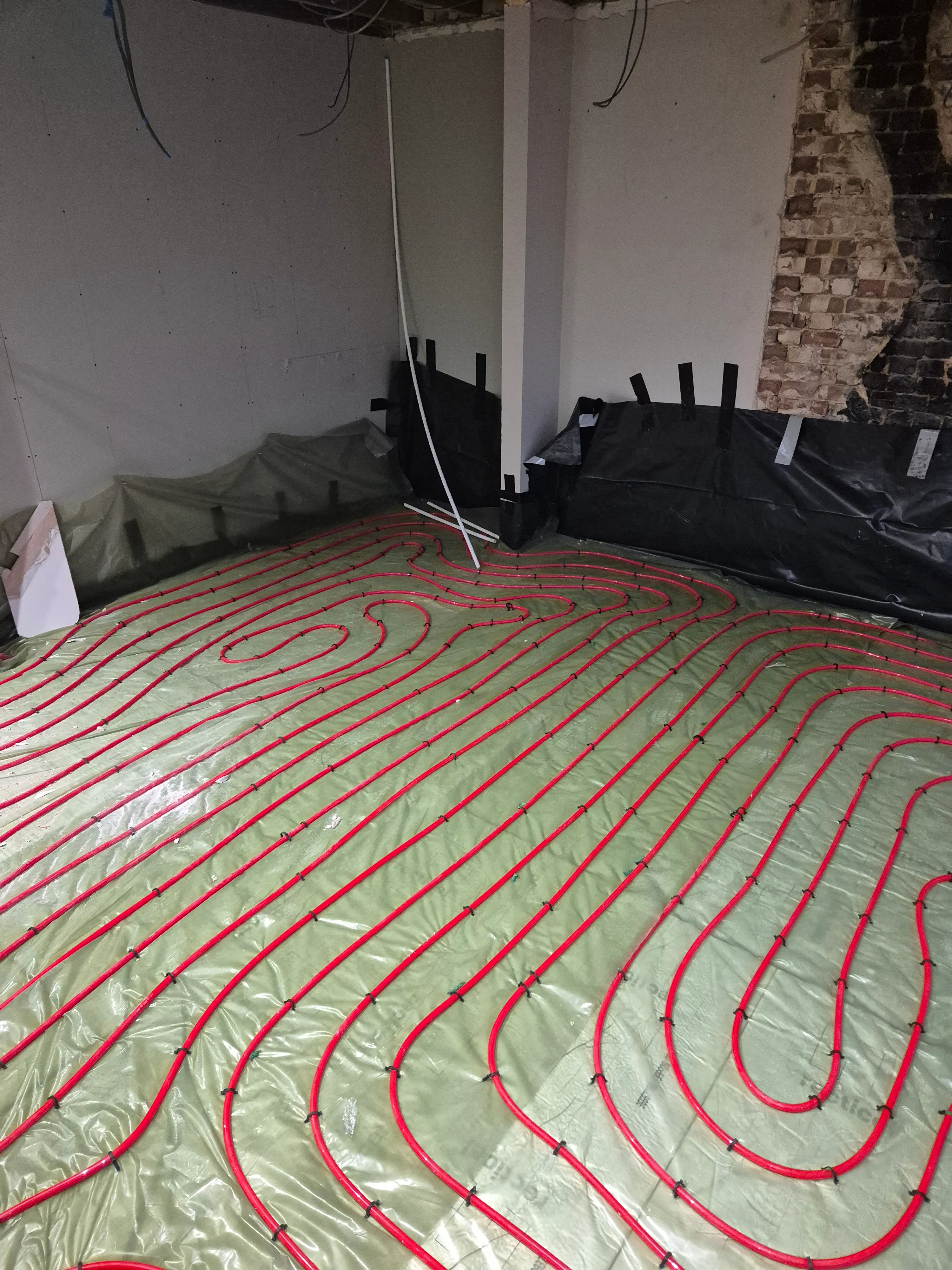 Underfloor heating pipe loops laid on insulation board, ready for screed