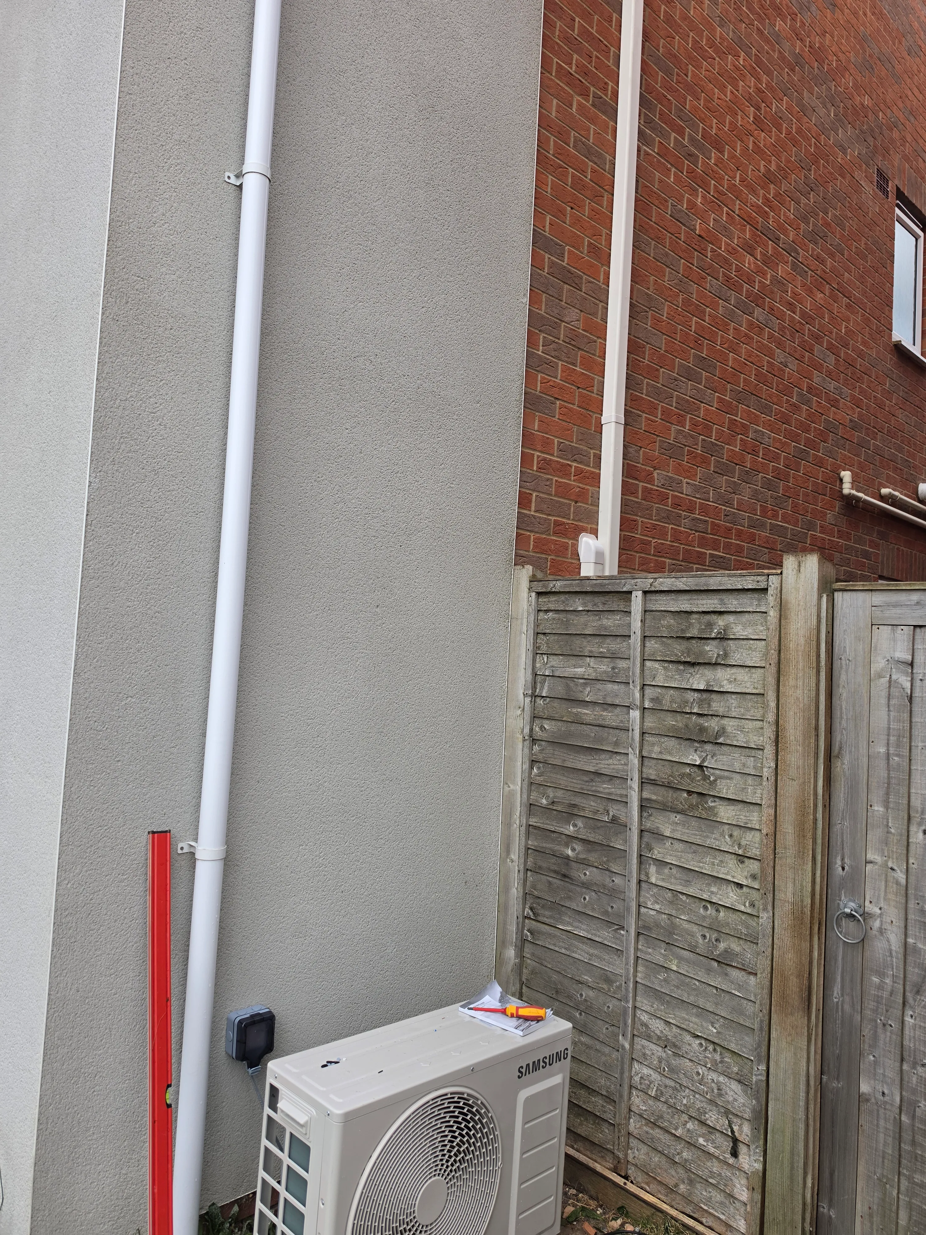 Outdoor condenser unit mounted on a flat roof with refrigerant pipework run